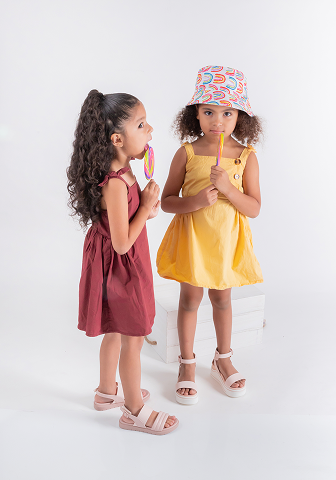 Two girls in colorful dresses holding candy, smiling